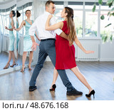 Man practicing samba with female partner in red in dance class. Стоковое фото, фотограф Яков Филимонов / Фотобанк Лори
