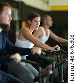 Sportive young girl doing air bike exercises in well-equipped gym. Стоковое фото, фотограф Яков Филимонов / Фотобанк Лори