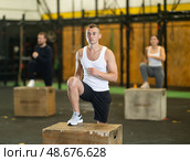 Sportive young guy doing step-up exercises with box during crossfit workout. Стоковое фото, фотограф Яков Филимонов / Фотобанк Лори