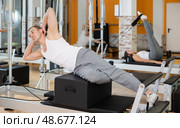 Man in different poses performs static and dynamic exercises on reformer. Стоковое фото, фотограф Яков Филимонов / Фотобанк Лори