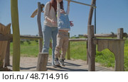 Mother helping her son doing pull ups at the playground. Стоковое видео, видеограф Константин Шишкин / Фотобанк Лори