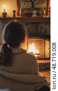 A wide-angle view of a cozy living room with a crackling fireplace, where a girl sits wrapped in a blanket, her oversize cardigan shining in fireplace light with Christmas festive decorated interior. Стоковое AI-видео, аниматор Sergey Grishin / Фотобанк Лори