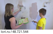 The mother and her son are busy fixing up their room, applying paint to the walls with a brush and roller. A friendly family, the new children's room in the house. Wall painting. Renovation concept. Стоковое видео, видеограф Ирина Старикова / Фотобанк Лори