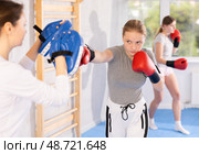 Girls works out strength and speed of boxing punch mitts with help of partner in boxing paws. Стоковое фото, фотограф Яков Филимонов / Фотобанк Лори
