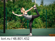A beautiful athletic woman is engaged in outdoor fitness in the summer. A young girl warms up in the sports arena. Fitness, good morning, workout, activity concept. Стоковое фото, фотограф Иван Карпов / Фотобанк Лори