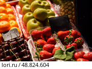 Colorful fruit display showcasing fresh strawberries, cherries, green apples, and vibrant oranges at a local market during early afternoon hours. Стоковое фото, фотограф Сергей Толмачёв / Фотобанк Лори