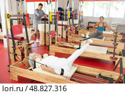 Elderly woman is engaged in Pilates simulator with cable and ropes for stretching leg muscles. Стоковое фото, фотограф Яков Филимонов / Фотобанк Лори
