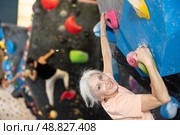 Mature female fitness climber training at bouldering gym.Woman rise up on artificial climbing wall. Стоковое фото, фотограф Яков Филимонов / Фотобанк Лори