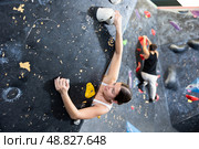 Female fitness climber training at bouldering gym. Young woman rise up on artificial climbing wall. Стоковое фото, фотограф Яков Филимонов / Фотобанк Лори
