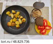 Bachelor dinner of homemade food. Lunch of fried potatoes in a pan, tomatoes and canned sprats. Стоковое фото, фотограф Сергей Пристяжнюк (Serg Zastavkin) / Фотобанк Лори