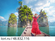 Famous tourist destinations view Thai - Woman solo traveler in red dress on Traditional Thai Longtail boat admiring a famous travel spot Thailand Three Rocks on Cheo Lan Lake in Khaosok Park in Surat Thani Province. Стоковое фото, фотограф Владимир Разгуляев / Фотобанк Лори