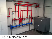 House heating system equipment. Pipelines. Basement mechanical room with condensing water heater, storage tank, plumbing systems. Plumbing service. Pipeline in boiler room. Pipes. Wall installation. Стоковое AI-изображение, AI-художник Марина Демидюк / Фотобанк Лори