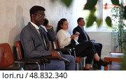 Serious-minded African male candidate siting on chair and waiting for job interview in hallway. Стоковое видео, видеограф Яков Филимонов / Фотобанк Лори