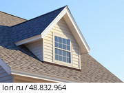 House Exterior. Roof Window. Second floor among blue sky. Mansard attic. Newly build houses. Gable roof with skylight, asphalt roofing, shingles. Residential Home. Vinyl Siding. Polymeric roof-tiles. Стоковое AI-изображение, AI-художник Марина Демидюк / Фотобанк Лори