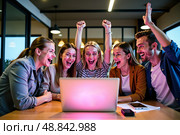 Группа молодых людей с восторгом смотрит на экран ноутбука в офисе / Group of people with a joyful mood watching a laptop screen in an office. Стоковое AI-изображение, AI-художник Валерий Лукин / Фотобанк Лори