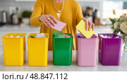Sorting colorful papers into labeled bins in a modern kitchen during a decluttering session. Стоковое AI-изображение, AI-художник Сергей Толмачёв / Фотобанк Лори