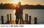 A couple sharing a quiet moment at sunset by the lake, golden light reflecting on the water, their silhouettes creating long shadows. Стоковое AI-видео, аниматор Sergey Grishin / Фотобанк Лори