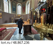 A woman lights a candle in the Holy Trinity Cathedral in Jerusalem. Редакционное фото, фотограф Irina Opachevsky / Фотобанк Лори