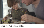 Father teaching his little son to solder electronic contacts at home. Стоковое видео, видеограф Скоробогатова Е. / Фотобанк Лори