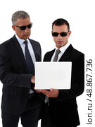 Businessmen wearing sunglasses and looking at a laptop. Стоковое фото, агентство Ingram Publishing / Фотобанк Лори