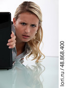 Annoyed woman peeking round her laptop. Стоковое фото, агентство Ingram Publishing / Фотобанк Лори
