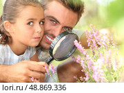 father and little daughter observing flowers with magnifying glass. Стоковое фото, агентство Ingram Publishing / Фотобанк Лори