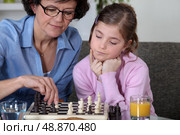 Girl and her grandmother playing chess. Стоковое фото, агентство Ingram Publishing / Фотобанк Лори