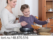 Teaching her daughter to make crepes. Стоковое фото, агентство Ingram Publishing / Фотобанк Лори