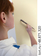 Woman passing brush over wall paper. Стоковое фото, агентство Ingram Publishing / Фотобанк Лори