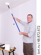 Man painting ceiling with roller. Стоковое фото, агентство Ingram Publishing / Фотобанк Лори