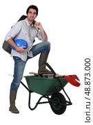 Tradesman with his foot propped up on a wheelbarrow. Стоковое фото, агентство Ingram Publishing / Фотобанк Лори