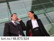 Pair of execs using a cellphone outside an office building. Стоковое фото, агентство Ingram Publishing / Фотобанк Лори