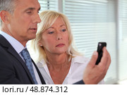 A team of business professionals reading a text message. Стоковое фото, агентство Ingram Publishing / Фотобанк Лори