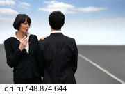 Conceptual shot of a business couple standing facing different directions on a highway. Стоковое фото, агентство Ingram Publishing / Фотобанк Лори