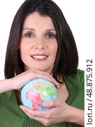 dark-haired smiling woman holding globe in both hands. Стоковое фото, агентство Ingram Publishing / Фотобанк Лори
