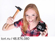 Amusing shot of young girl trying to break open her piggy bank with a hammer. Стоковое фото, агентство Ingram Publishing / Фотобанк Лори