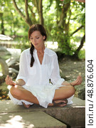 Woman in white sitting cross legged in the park. Стоковое фото, агентство Ingram Publishing / Фотобанк Лори