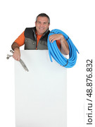 Plumber with materials and a board left blank for your message. Стоковое фото, агентство Ingram Publishing / Фотобанк Лори