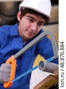 young man is cutting a pvc pipe with a saw. Стоковое фото, агентство Ingram Publishing / Фотобанк Лори