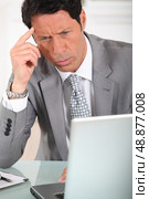 Businessman with a puzzled expression looking at a computer screen. Стоковое фото, агентство Ingram Publishing / Фотобанк Лори
