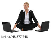 Woman sitting cross-legged in front of two computers. Стоковое фото, агентство Ingram Publishing / Фотобанк Лори