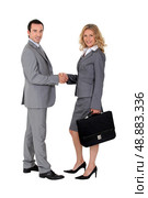 Smart suited man and woman shaking hands. Стоковое фото, агентство Ingram Publishing / Фотобанк Лори