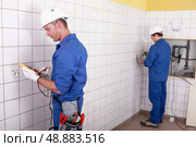 Workteam installing electrics in a tiled room. Стоковое фото, агентство Ingram Publishing / Фотобанк Лори