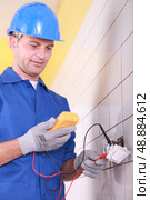 electrician is checking an outlet with an ammeter. Стоковое фото, агентство Ingram Publishing / Фотобанк Лори