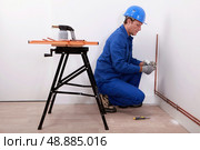 Plumber fitting new pipes to wall. Стоковое фото, агентство Ingram Publishing / Фотобанк Лори