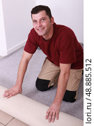 Horizontal image of a man laying carpet. Стоковое фото, агентство Ingram Publishing / Фотобанк Лори