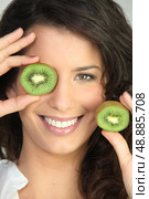 Woman covering eye with kiwi. Стоковое фото, агентство Ingram Publishing / Фотобанк Лори
