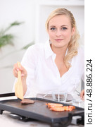 Woman cooking seafood and meat on a plancha. Стоковое фото, агентство Ingram Publishing / Фотобанк Лори