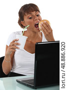 Woman eating at her desk. Стоковое фото, агентство Ingram Publishing / Фотобанк Лори
