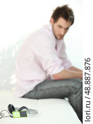 young man looking at his mp3 player. Стоковое фото, агентство Ingram Publishing / Фотобанк Лори